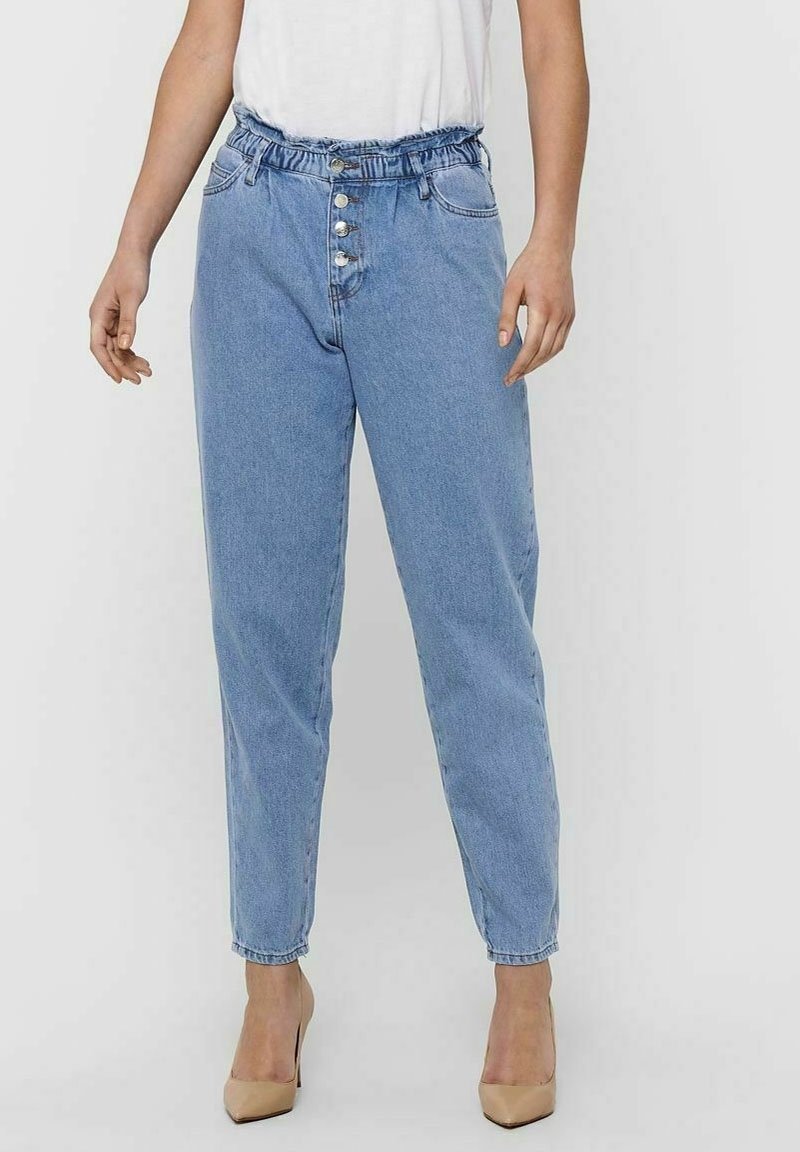 Blue denim high-waisted pants with an elastic waistband, five-button closure, front pockets, and tapered legs, paired with beige shoes.