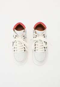 Vita höga sneakers med perforerade detaljer, snörning, röda accenter vid kragen och bruna innersulor. Släta och texturerade material.
