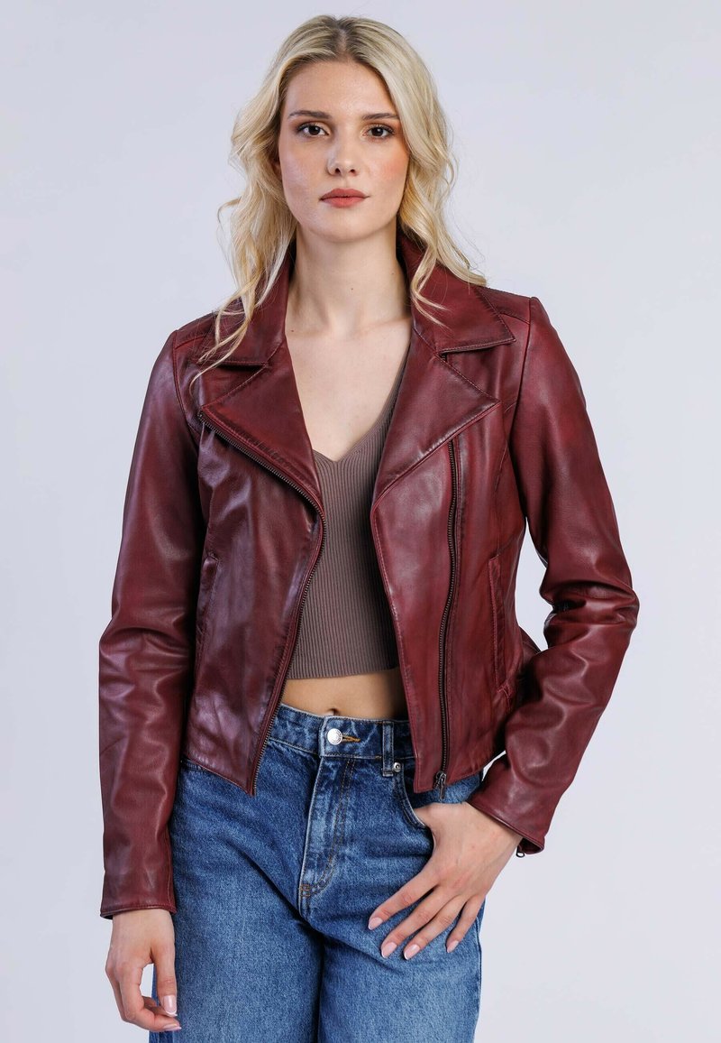 Burgundy lädermotorcykeljacka med snedkrage, dragkedjestängning och figursydd design, kombinerad med högmidjade denimjeans.