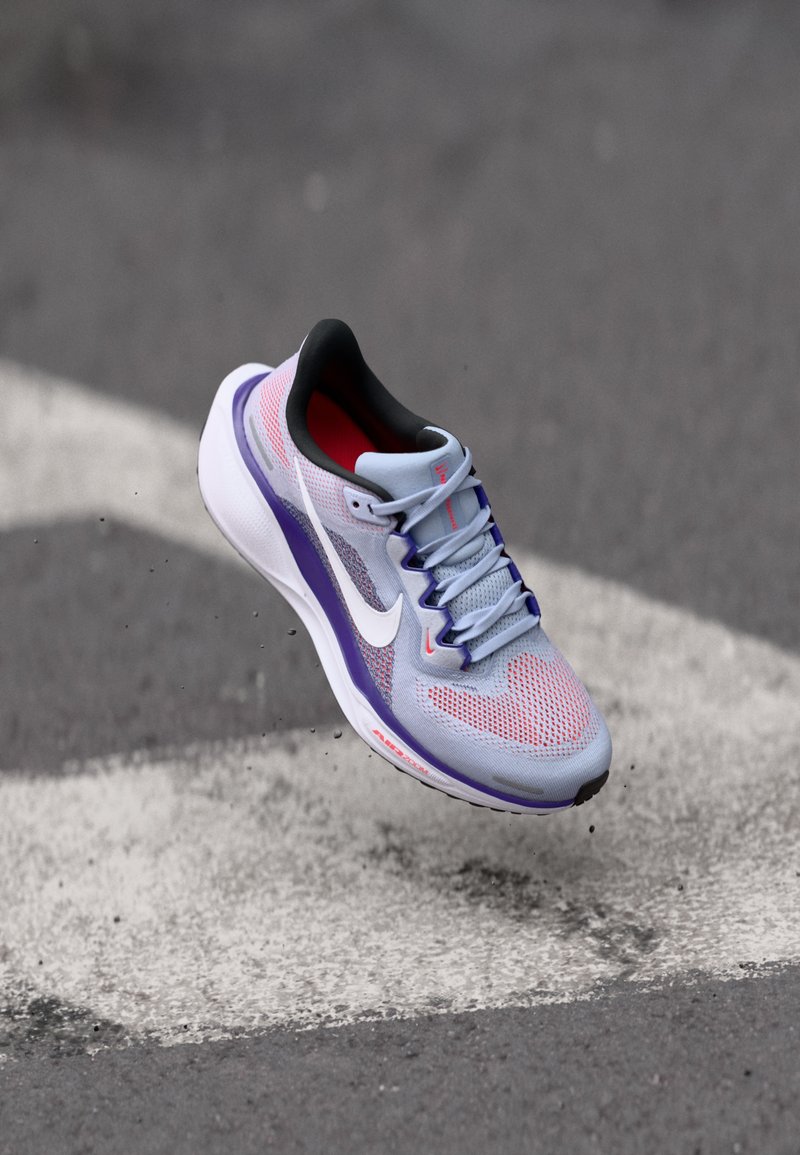 Baskets de course bleu clair avec un dessus en mesh, accents roses et violets, logo swoosh blanc et rembourrage intérieur noir.