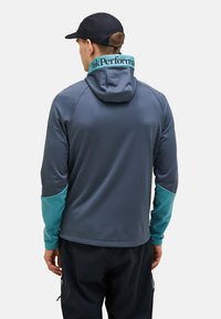 Hættejakke i mørkegrå med turkise detaljer på ærmer og krave. Har et blødt, tekstureret stof og atletisk pasform.