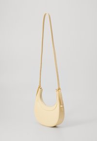 Yellow leather shoulder bag with a curved shape, adjustable strap, and gold-tone hardware accents. Smooth texture and minimalist design.