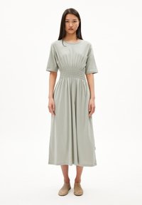 Light green cotton dress featuring a relaxed fit, short sleeves, and a smocked waist, extending to a midi length with a smooth texture.