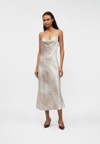 Σατέν φόρεμα με λείο υφή, σε ανοιχτό μπεζ χρώμα με διακριτικό animal print. Διαθέτει λεπτές ράντες και ρέουσα άκρη.