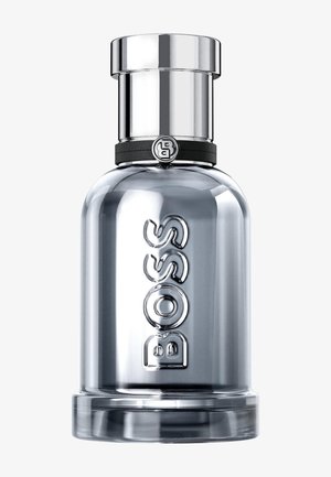 Bottiglia di profumo in vetro trasparente con tappo argentato riflettente e il nome del marchio "BOSS" inciso verticalmente sulla parte anteriore.