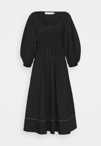 Svart bomullsklänning med fyrkantig halsringning, puffärmar, elastisk midja och en flerlagerskjol med vit sömdetalj vid fållen.