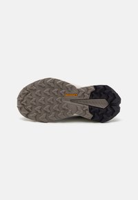 Semelle de chaussure présentant un design robuste avec un mélange de caoutchouc gris clair et noir. Le motif de la semelle comprend des crampons multidirectionnels pour une traction optimale.