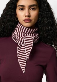 Gebreide sjaal met gestreept patroon in kastanjebruin en crème, met een puntig ontwerp aan het uiteinde en een zachte textuur, gedragen over een donker shirt.