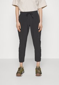 Lösa mörkgrå byxor med elastisk midja och dragsko. Har cargofickor på sidorna. Matchas med gröna och bruna sneakers.