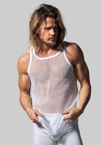 White mesh tank top with a loose fit and a crew neckline, worn over white fitted bottoms, highlighting a textured pattern.