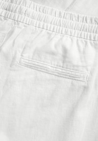 Pantalones cortos de lino blancos con una cinturilla elástica fruncida y un único bolsillo trasero con cierre plano. Textura suave y tejido ligero.
