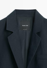 Donker marineblauw colbert met een notch-reverskraag en een label van Massimo Dutti genaaid aan de binnenkant van de hals, gemaakt in Portugal.