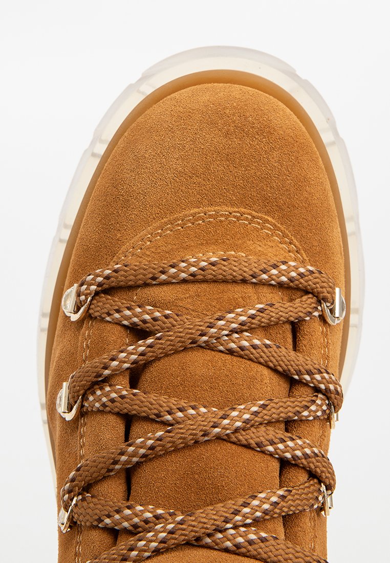 Braune Wildlederschuhe mit runder Zehenform und beigefarbenem Gummisohle. Mit braunen und weißen gemusterten Schnürsenkeln und metallischen Ösen zur sicheren Schnürung.