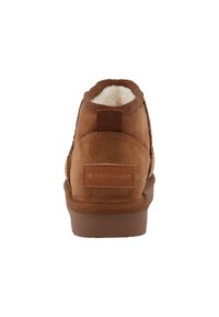 Braune Wildleder-Ankle Boots mit einem weichen Fleece-Futter, strukturiertem Material, einem Ziehschlauf und einer Gummisohle mit dezentem Branding auf der Rückseite.