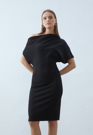 Black off-shoulder dress made of sleek, stretchy fabric; form-fitting through the body with a knee-length hem and smooth texture.