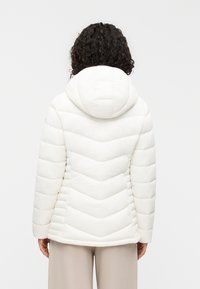 Λευκό μπουφάν τύπου puffer με σχέδιο καπιτονέ σε σχήμα ζιγκ-ζαγκ, διαθέτει κουκούλα και ελαστικές μανσέτες. Μαλακή, λεία υφή με κομψή σιλουέτα.