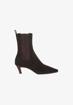 Zwarte suède enkellaars met een spitse neus, elastische zijkanten en een slanke gestapelde hak. Gladde textuur met een matte afwerking.