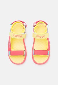 Kolorowe dziecięce sandały z żółtą podeszwą w wzór plastra miodu, czerwonymi i pastelowymi paskami oraz regulowanymi zapięciami. Widoczny logo.