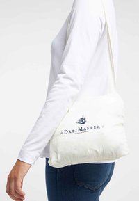 Person som bär en vit långärmad skjorta och blå jeans bär en vit axelväska med "Drei Master"-logotypen och en fartygsillustration.
