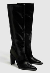 Botas de cuero negro hasta la rodilla con acabado brillante, punta puntiaguda y atrevido tacón block. Diseño elegante con detalles de costura mínimos.