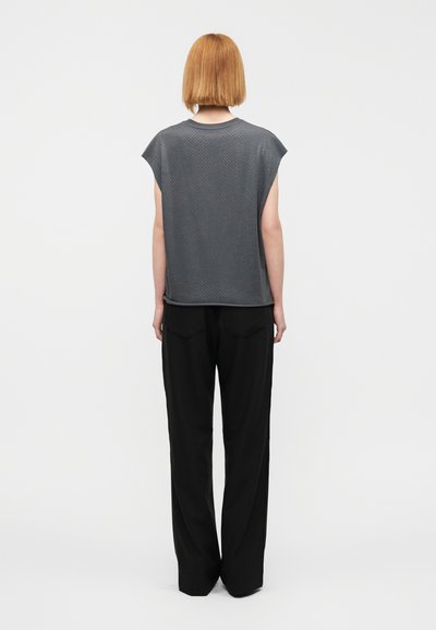 Γκρι κοντομάνικη μπλούζα με υφή, συνδυασμένη με φαρδιά μαύρη παντελόνια. Το σύνολο έχει χαλαρή σχεδίαση και διακριτικές λεπτομέρειες.
