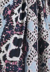 Stoffe mit einem blauen, schwarzen und rosa abstrakten Muster; gewobene Textur mit Falten; geometrische Formen und pixelierte Details sind sichtbar.