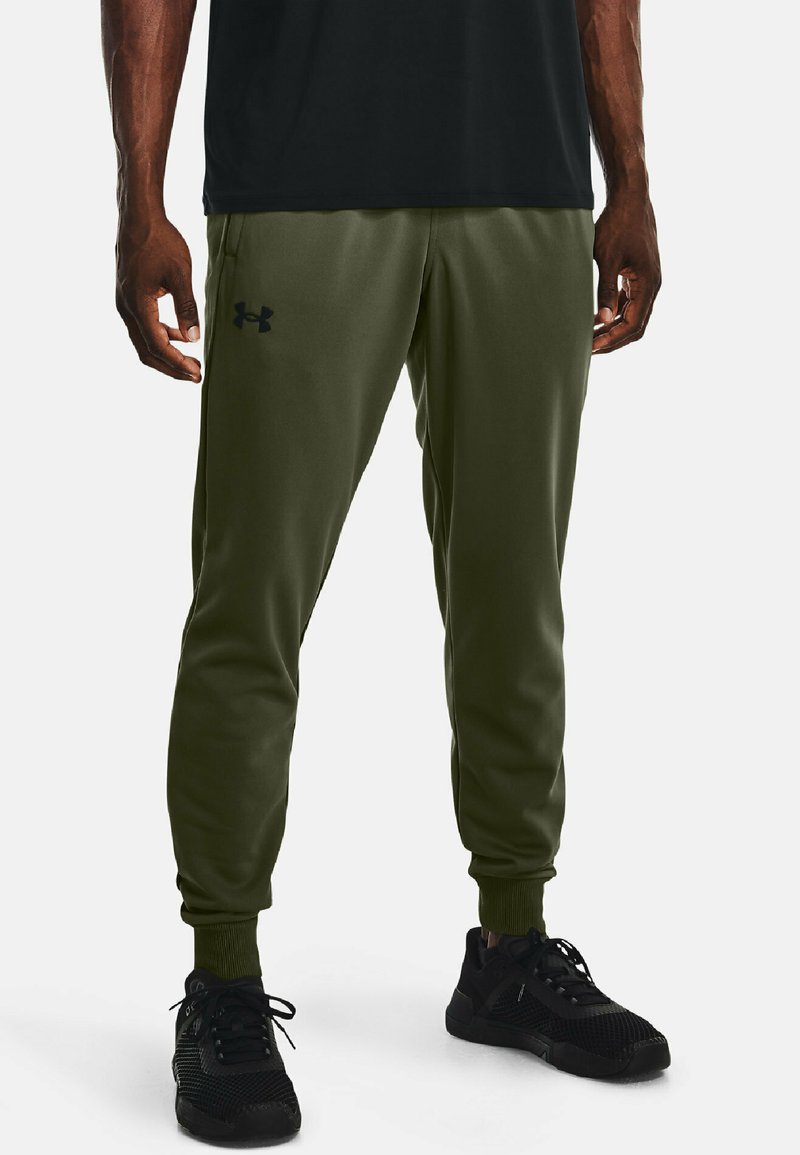 Jogging en olive vert, fabriqués en tissu lisse, avec un cordon de serrage à la taille et le logo noir Under Armour sur la cuisse gauche.