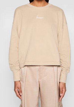 Sudadera beige de manga larga con texto "boss" en el pecho, combinada con pantalones de satén beige claro.