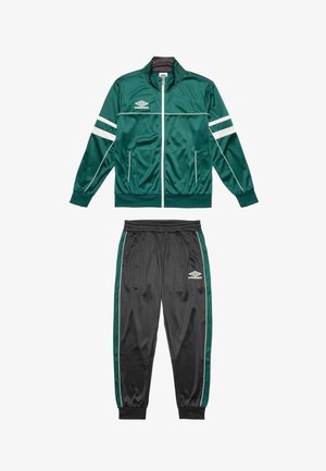 Tumma vihreä satiininen track takki, jossa on valkoiset raidat, vetoketjusuljenta ja sivutaskut. Yhteensopivat mustat housut vihreillä yksityiskohdilla ja joustovyötärö.