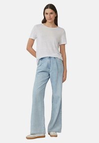 T-shirt à manches courtes gris clair associé à un jean en denim bleu clair taille haute et à jambes larges. Look décontracté et ample avec un design simple.