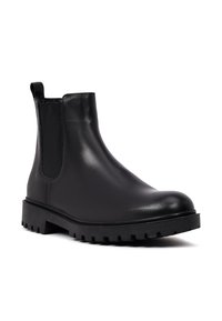Stivale Chelsea in pelle nera con pannelli laterali elasticizzati, punta tonda e suola in gomma testurizzata. Finitura liscia, progettato per essere indossato facilmente.