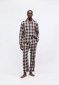 Kariertes Flanell-Pyjamaset mit einem Hemd mit Knöpfen und passenden Hosen in Marineblau, Creme und Rot. Leichtes Material mit lockerer Passform.