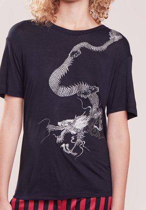 Person wearing a black t-shirt with a detailed white dragon design extending from shoulder to waist.