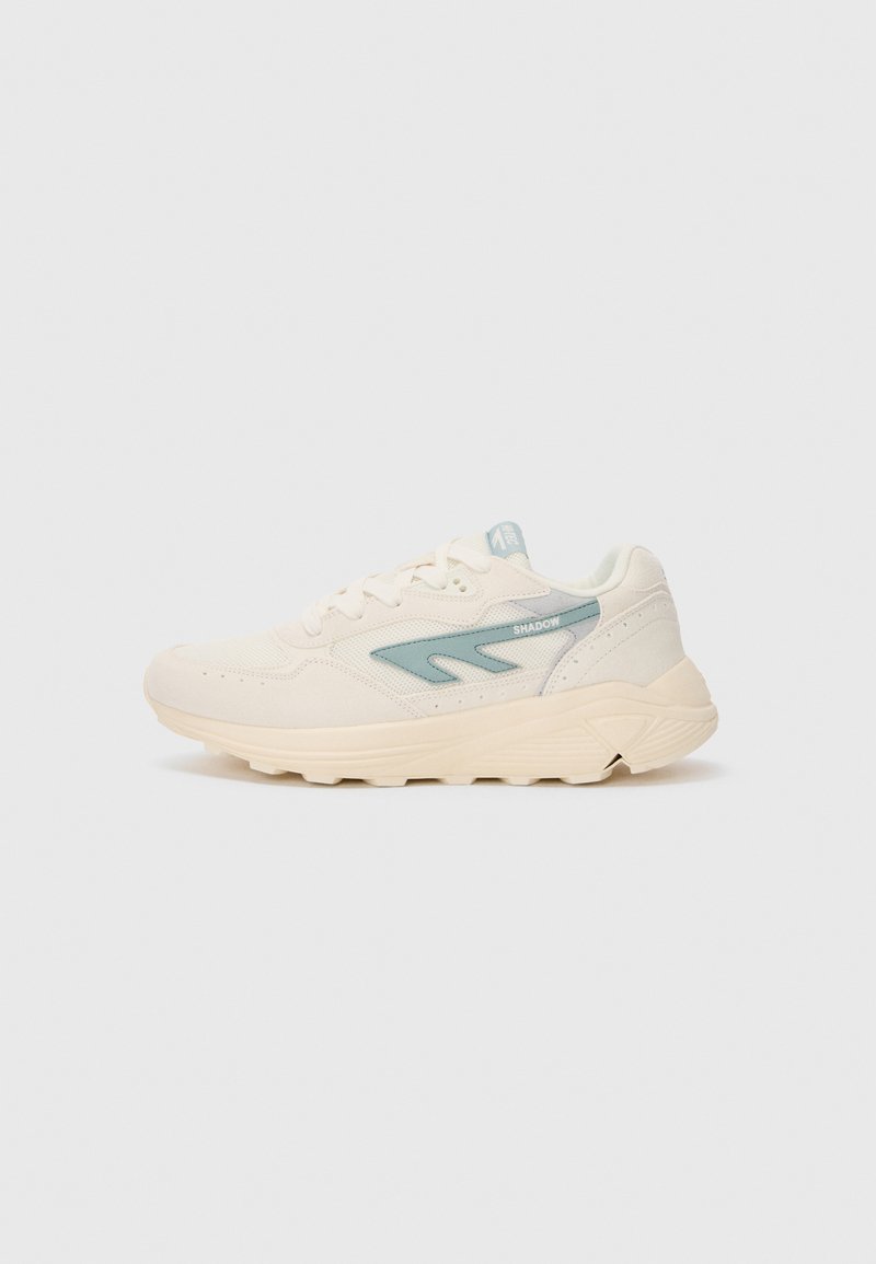 Zapatillas deportivas color beige claro con un upper de tejido texturizado, acentos turquesas y una suela acolchada que presenta ranuras para mayor tracción.