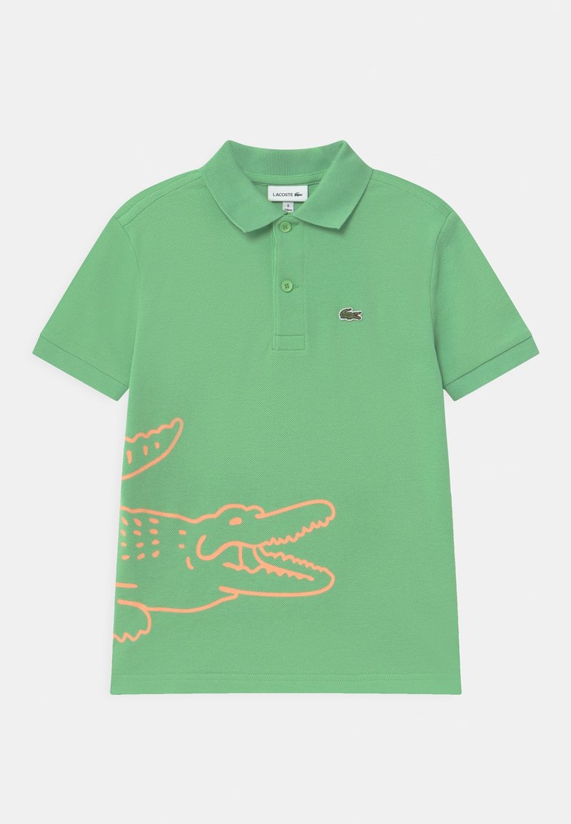 Polo vert à manches courtes avec col, deux boutons, petit logo crocodile Lacoste sur la poitrine et grand motif crocodile orange en contour en bas.