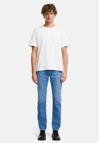 Biała koszulka z krótkim rękawem o okrągłym dekolcie, zestawiona z jasnoniebieskimi dżinsami prostymi i czarnymi sznurowanymi butami.