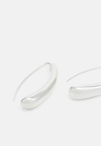 Silvriga ringörhängen med en slät, avlång oval form och en polerad yta. Designen har en tunn tråd för säkerställande.
