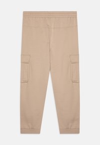 Pantalons cargo beiges avec une texture douce, taille élastique et chevilles resserrées. Comprend deux poches cargo latérales et des coutures détaillées.