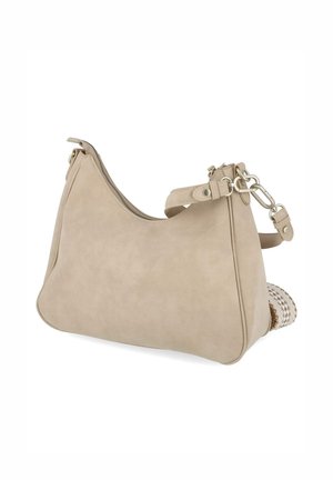 Sac à bandoulière en cuir beige avec ferrures argentées, fermeture éclair et bandoulière amovible, posé sur une surface blanche avec un objet tissé partiellement visible.