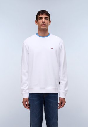 Witte sweatshirt gemaakt van zachte stof met een ronde hals, voorzien van een blauwe binnenkraag en een klein logo op de borst. Draagt blauwe jeans.