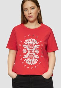 Rode katoenen t-shirt met korte mouwen en een ronde halslijn. Kenmerkt een wit grafisch ontwerp van gestileerde bloemen en de tekst "LAAT JE ANGSTEN VERVAGEN."