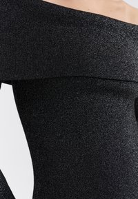 Zwarte off-shoulder jurk met een aansluitend ontwerp, gemaakt van een gestructureerd, glanzend materiaal dat licht weerkaatst. Heeft een rechte halslijn.