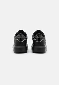 Black leather sneakers featuring a rounded shape, cushioned sole, and embossed "KARL LAGERFELD" branding on the heel.