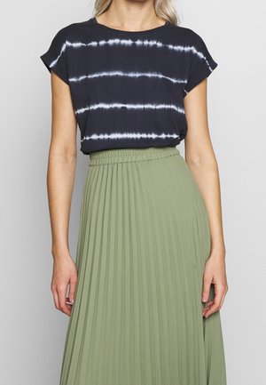 Czarna bluzka tie-dye z krótkimi rękawami w połączeniu z plisowaną oliwkowozieloną spódnicą. Bluzka zdobiona jest białymi, poziomymi paskami.