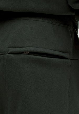 Tessuto di felpa verde scuro con tasca con zip, superficie liscia e vestibilità comoda, con dettagli di cucitura lungo le cuciture.