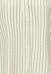 Tissu crème avec de fines rayures verticales brunes et une texture en points en relief formant un motif subtil.