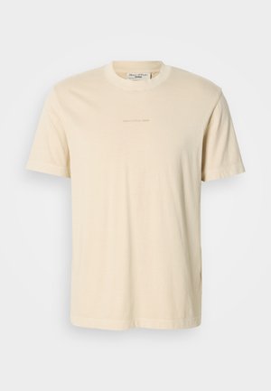 Light beige cotton t-shirt with a round neckline and short sleeves. Features subtle printed branding on the chest. Smooth texture.