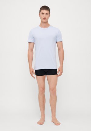 T-shirt bleu clair à manches courtes en tissu doux, associé à un short boxer noir. Le t-shirt a un col rond et une coupe ajustée.