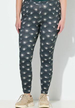 Strak zittende legging gemaakt van rekbare stof, met een donkere achtergrond en een herhalend waaierpatroon in lichtgrijs en witte accenten.