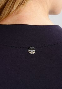Marineblauwe stof top met een brede halslijn, voorzien van een klein zilveren label met de tekst "rich&royal" aan de achterkant, genaaid met een subtiele textuur.